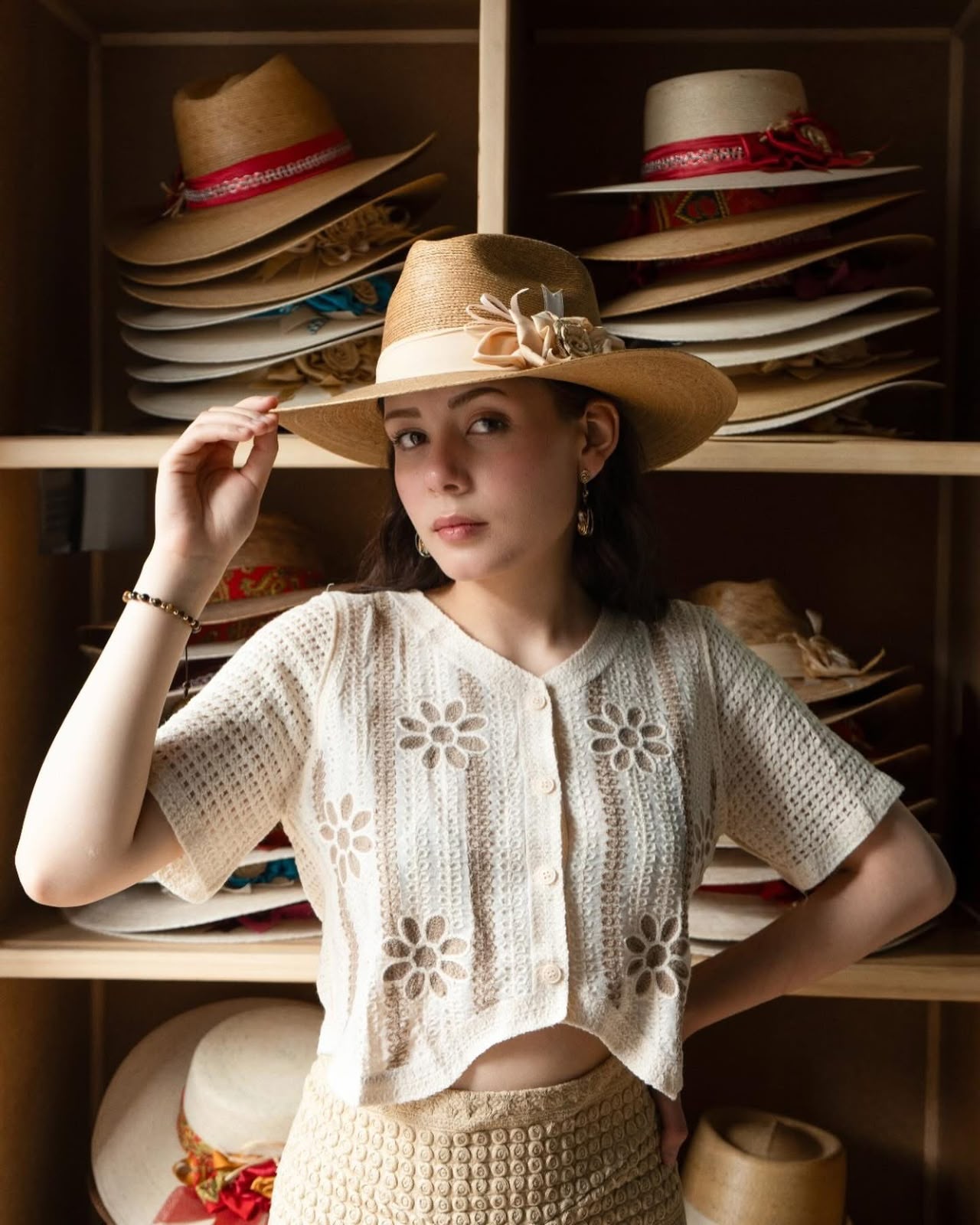 Sombrero de ala ancha con flores y blusa blanca de encaje.